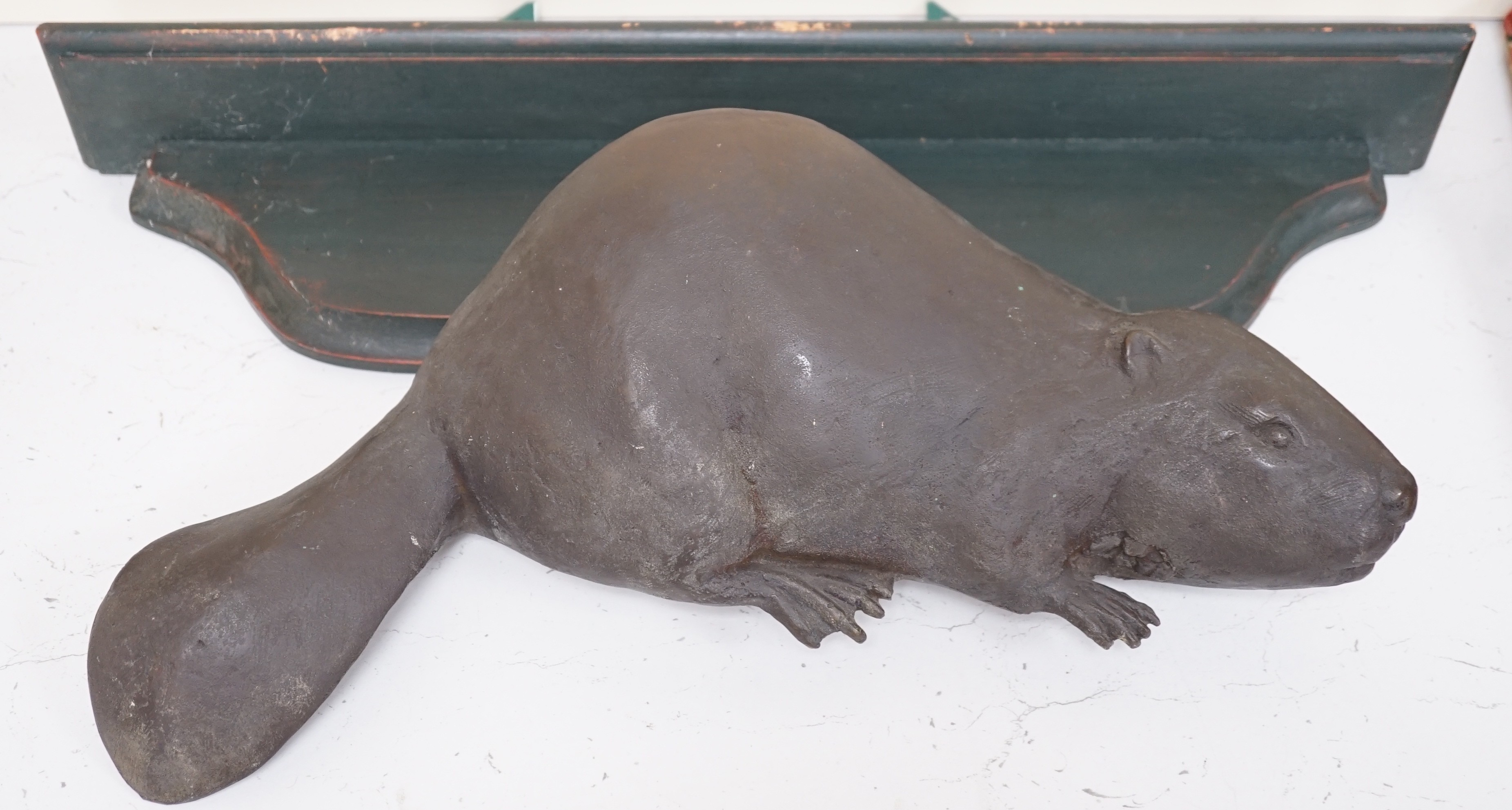 A bronze relief of a beaver and shaped green wall bracket